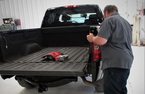 photo of man replacing truck tail light